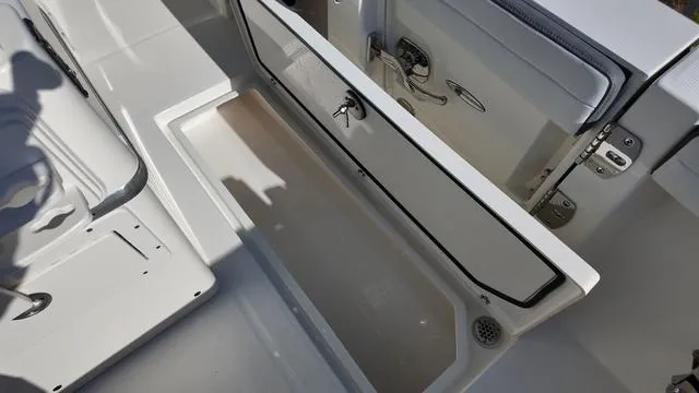 Slide: The Image of 2025 Cobia 265 CC boat storage compartment with open hatch, showcasing interior space. - 17