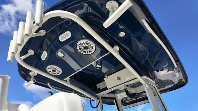 Slide: The Image of 2025 Cobia 265 CC boat roof with speakers and rod holders against blue sky. - 24