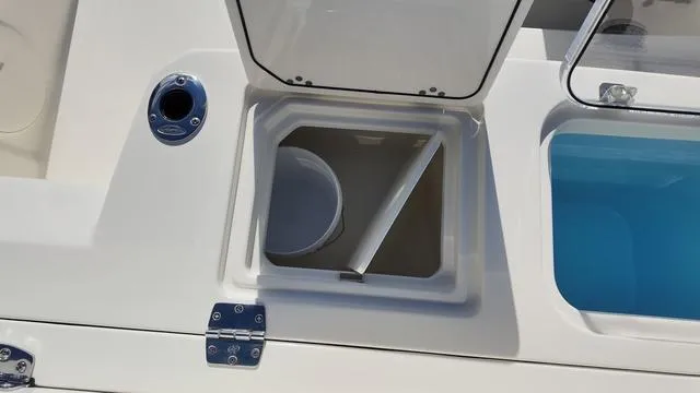 Slide: The Image of 2025 Cobia 265 CC boat storage compartment with open lid and bucket. - 8