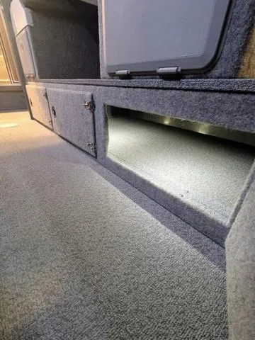 Slide: The Image of Interior storage compartment of 2025 Thunder Jet Pilot 26' boat, featuring carpeted flooring. - 29