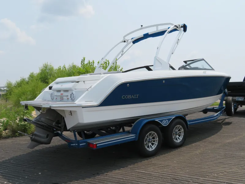 Slide: The Image of 2025 Cobalt CS23 boat on trailer, blue and white design, parked outdoors. - 3