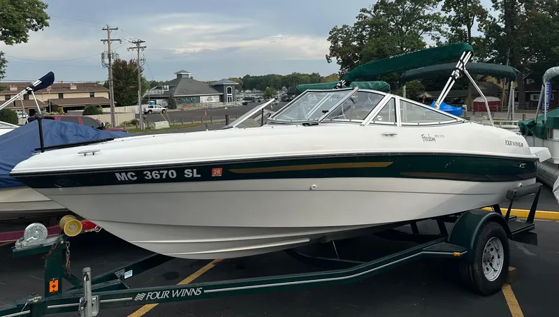 The Image of 2003 Four Winns Freedom 180F/S boat on trailer, parked outdoors. - 0