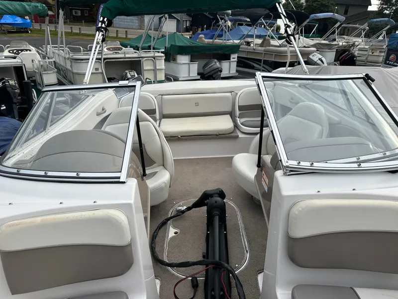 Slide: The Image of 2003 Four Winns Freedom 180F/S boat interior with seating and windshield, docked at marina. - 24