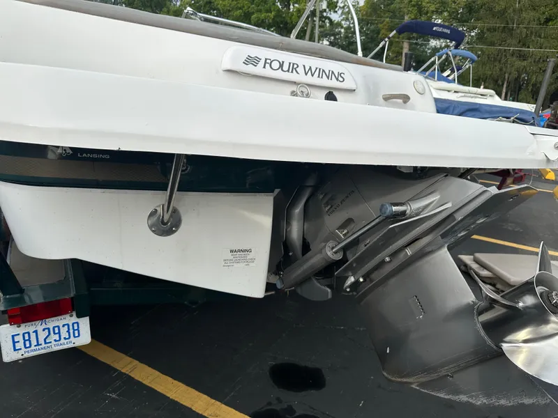 Slide: The Image of 2003 Four Winns Freedom 180F/S boat stern with outboard motor in parking lot. - 5