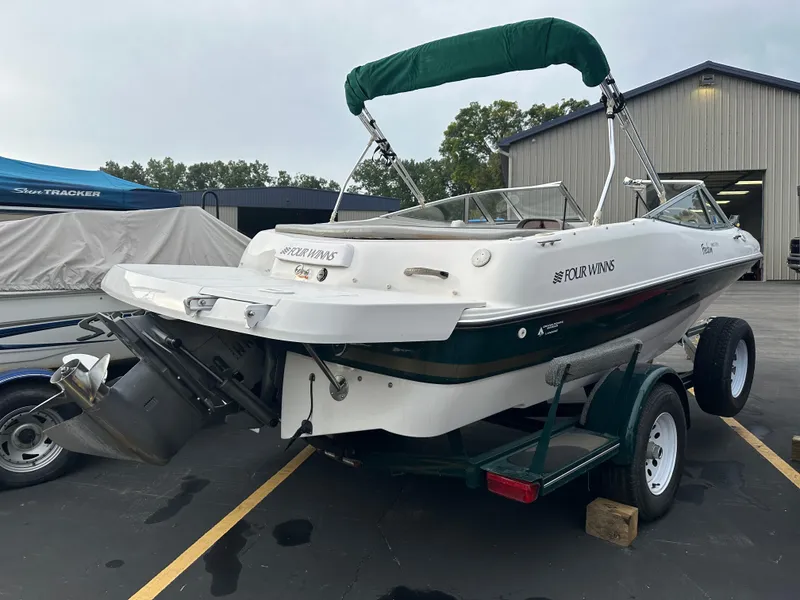 Slide: The Image of 2003 Four Winns Freedom 180F/S boat on trailer, parked outdoors near a building. - 7