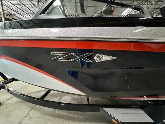 Slide: The Image of 2022 Tigé 23ZE boat with sleek black and red design in a warehouse. - 16
