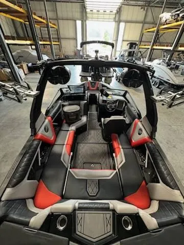 Slide: The Image of 2022 Tigé 23ZE boat interior with red and black seating in a warehouse. - 19