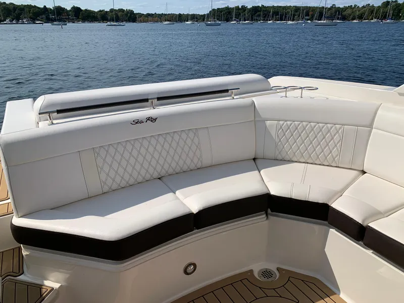Slide: The Image of 2019 Sea Ray SLX 310 boat with white leather seating, docked by a serene lake. - 12
