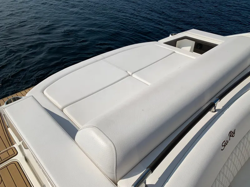 Slide: The Image of 2019 Sea Ray SLX 310 boat with white cushioned seating, docked on calm water. - 13