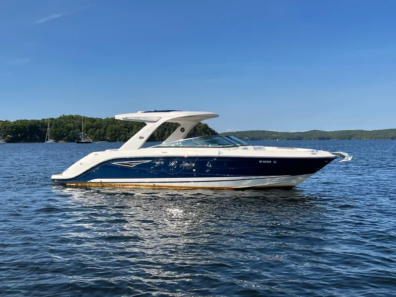 Slide: The Image of 2019 Sea Ray SLX 310 boat on a calm lake under clear blue skies. - 2