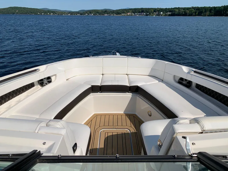 Slide: The Image of 2019 Sea Ray SLX 310 boat interior with white seating, on a serene lake. - 24