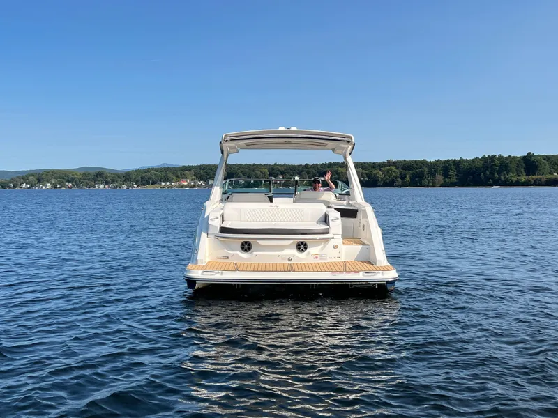 Slide: The Image of 2019 Sea Ray SLX 310 boat on a serene lake with clear blue skies. - 44