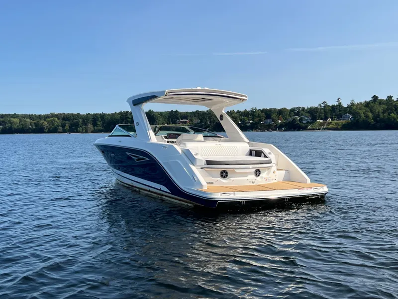 Slide: The Image of 2019 Sea Ray SLX 310 boat on a serene lake under clear blue skies. - 46