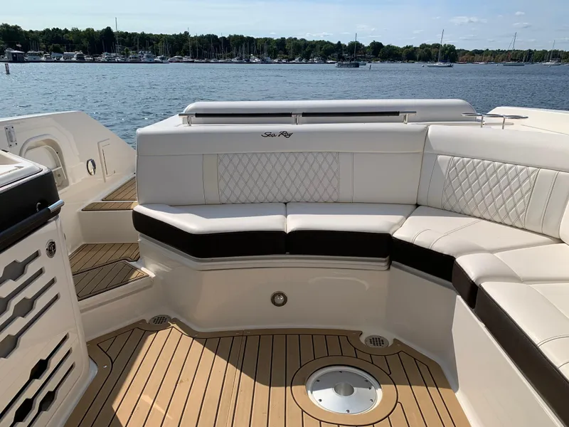 Slide: The Image of 2019 Sea Ray SLX 310 boat with luxurious seating and teak flooring, docked by a serene lake. - 9