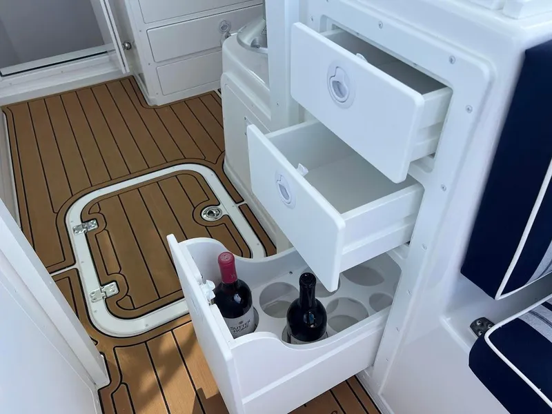 Slide: The Image of 2025 Steiger Craft 255 Annapolis boat interior with open storage drawers and wine bottles. - 23