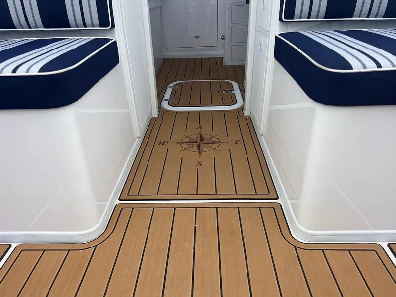 Slide: The Image of 2025 Steiger Craft 255 Annapolis boat interior with striped seating and compass design flooring. - 25
