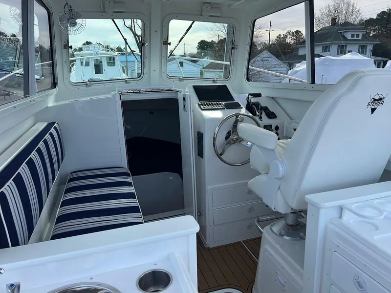 Slide: The Image of 2025 Steiger Craft 255 Annapolis boat interior with striped seating and steering console. - 29