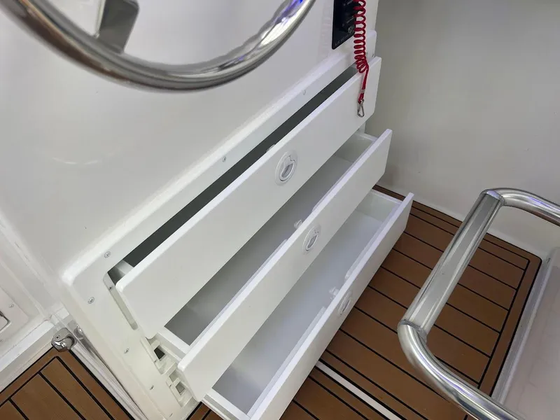 Slide: The Image of Open storage drawers on 2025 Steiger Craft 255 Annapolis boat with teak flooring. - 34