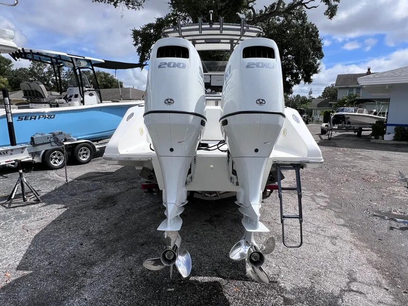 Slide: The Image of Twin outboard motors on a Dakota 32 cc 2023 Suzuki boat, parked outdoors. - 2