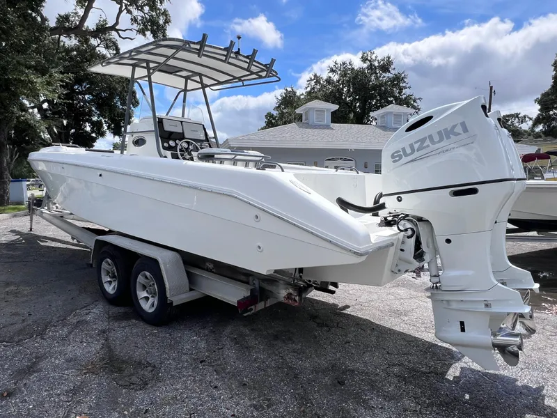 Slide: The Image of White Dakota 32 cc boat with Suzuki motor on trailer, parked outdoors. - 3