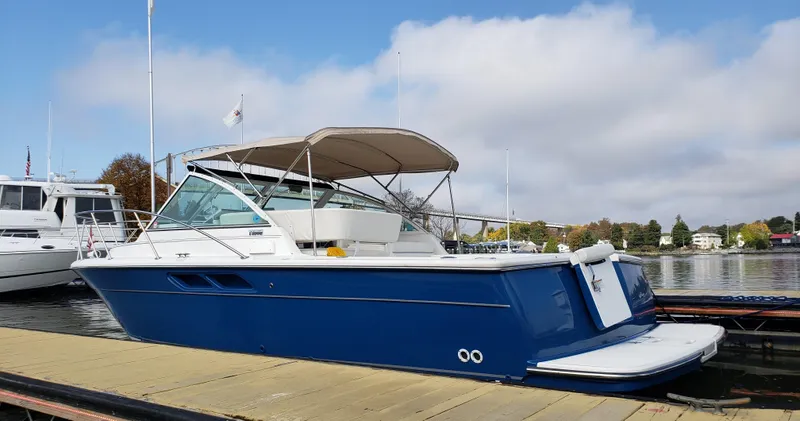 Slide: The Image of 2006 Tiara Yachts 2900 Coronet docked, blue hull, beige canopy, calm waters. - 7
