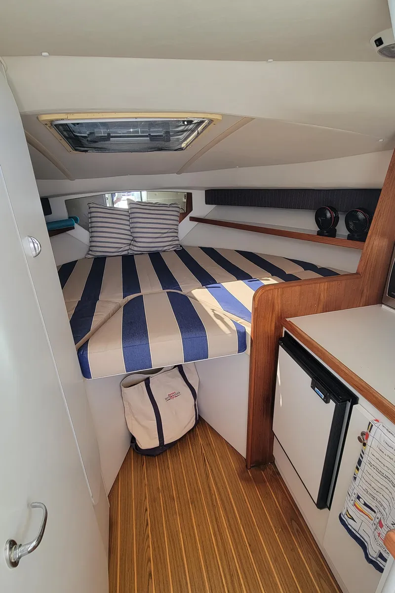 Slide: The Image of 2006 Tiara Yachts 2900 Coronet cabin interior with striped bedding and compact kitchenette. - 19