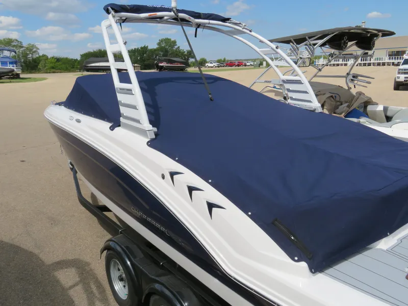 Slide: The Image of 2025 Chaparral 23 SSi boat with blue cover on trailer, parked outdoors. - 15