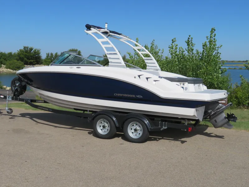 Slide: The Image of 2025 Chaparral 23 SSi boat on trailer by a lake, clear blue sky. - 2