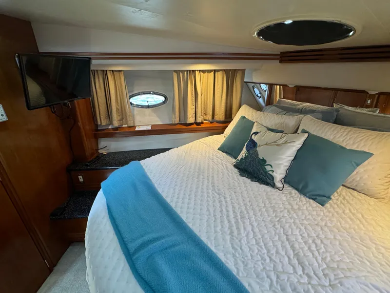 Slide: The Image of Luxurious bedroom in 2000 Carver 530 Voyager Pilothouse yacht with cozy bedding and porthole windows. - 39