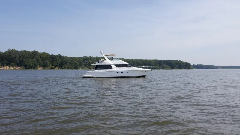 Slide: The Image of 2000 Carver 530 Voyager Pilothouse yacht on a calm lake with forested shoreline. - 44