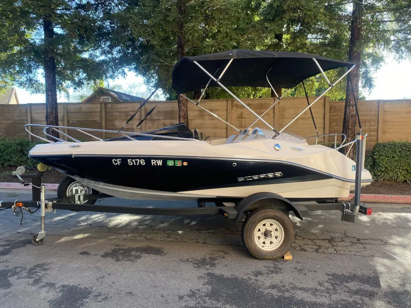 Slide: The Image of 2015 Scarab 165 Standard boat on trailer with canopy, parked outdoors. - 1