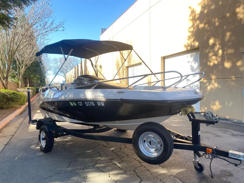 Slide: The Image of 2015 Scarab 165 Standard boat on trailer with canopy, parked outdoors. - 15