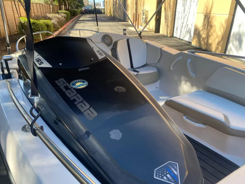 Slide: The Image of 2015 Scarab 165 Standard boat interior with seating and dashboard, parked outdoors. - 16