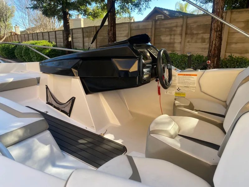 Slide: The Image of 2015 Scarab 165 Standard boat interior with steering wheel and seating, parked outdoors. - 21