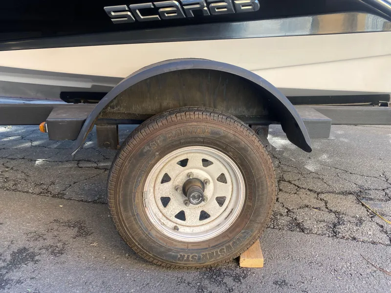 Slide: The Image of Trailer wheel of a 2015 Scarab 165 Standard boat on cracked pavement. - 22