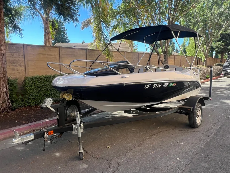 Slide: The Image of 2015 Scarab 165 Standard boat on trailer, parked outdoors with trees in the background. - 23