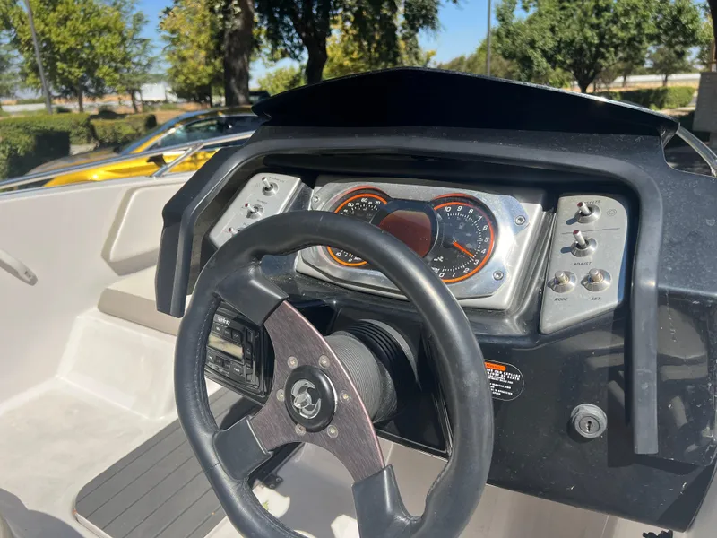 Slide: The Image of 2015 Scarab 165 Standard boat dashboard with steering wheel and gauges in sunlight. - 28
