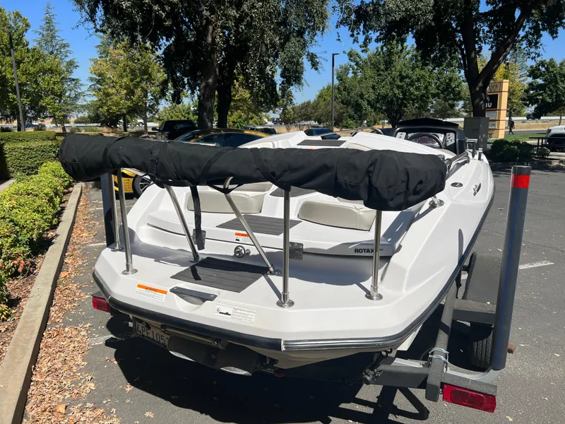 Slide: The Image of 2015 Scarab 165 Standard boat on trailer in parking lot, surrounded by trees. - 30