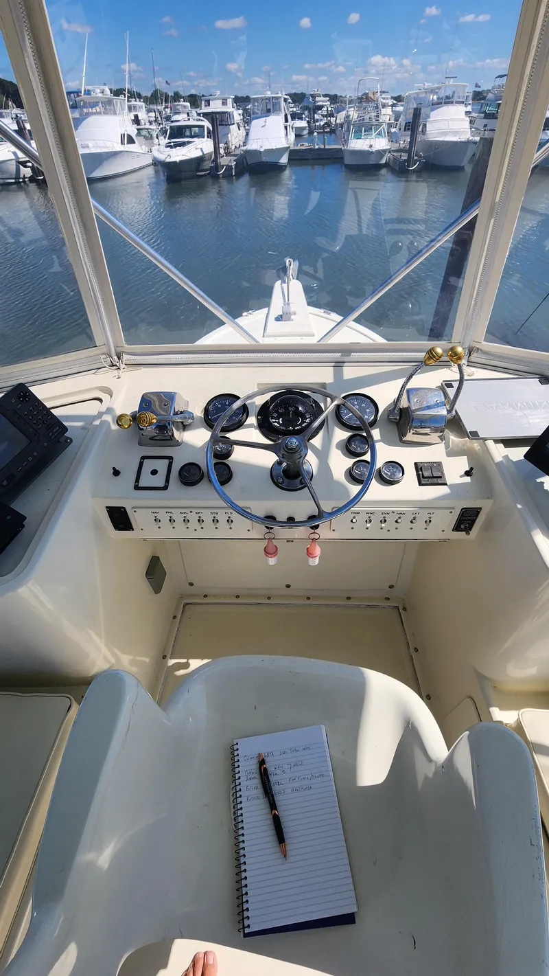 Slide: The Image of Helm of 1969 Hatteras 36 Sport Fisherman with marina view, featuring classic controls and notebook. - 17