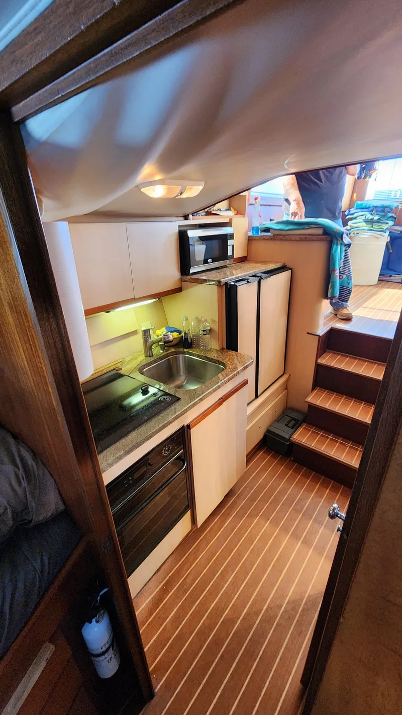 Slide: The Image of 1969 Hatteras 36 Sport Fisherman interior with compact kitchen and wooden flooring. - 29