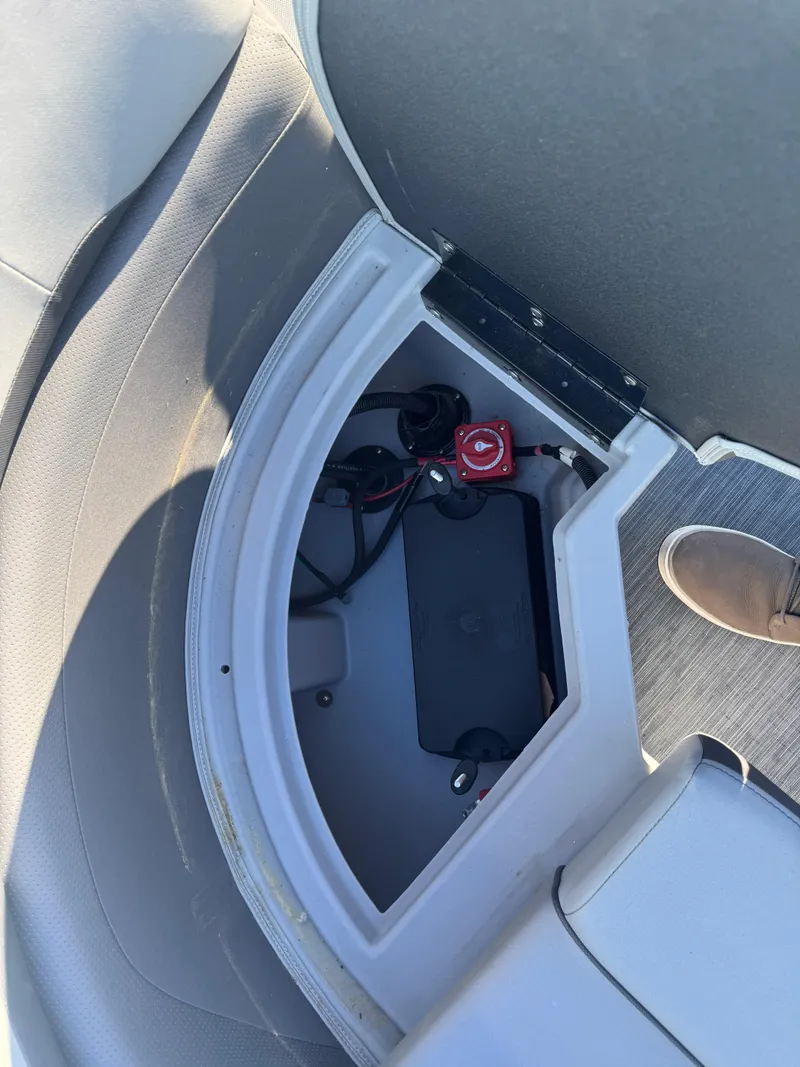 Slide: The Image of 2023 Bennington 23SX Swingback boat storage compartment with visible wiring and battery switch. - 10