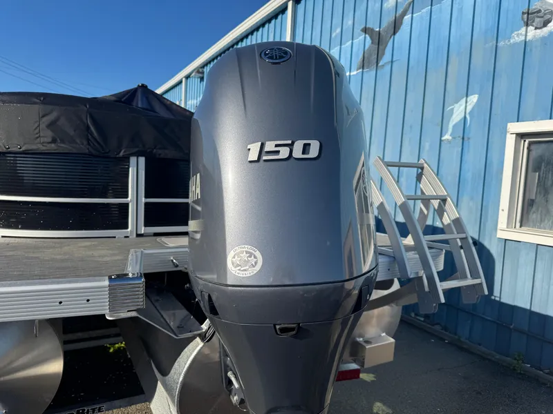Slide: The Image of 2023 Bennington 23SX Swingback with Yamaha 150 outboard motor, parked near blue building. - 12