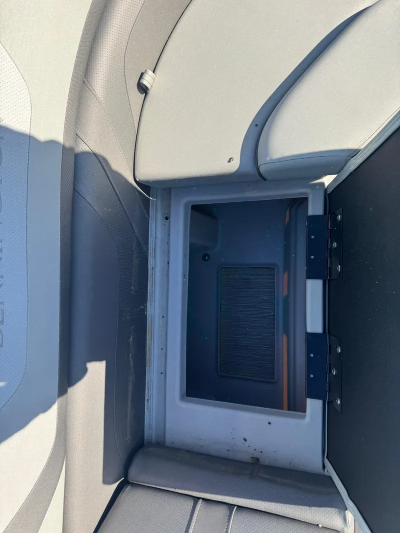 Slide: The Image of 2023 Bennington 23SX Swingback storage compartment with open lid, showcasing interior space. - 9