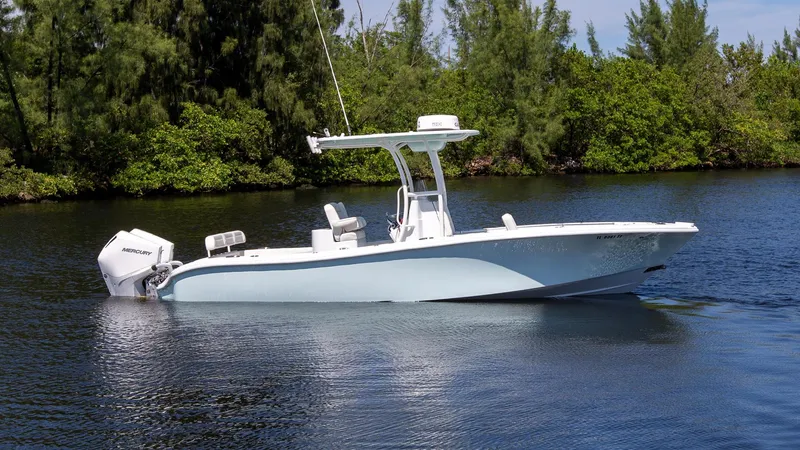 Slide: The Image of 2022 Yellowfin 26 Hybrid boat on calm water, surrounded by lush greenery. - 0