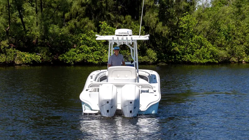 Slide: The Image of 2022 Yellowfin 26 Hybrid boat on calm water, surrounded by lush greenery. - 1