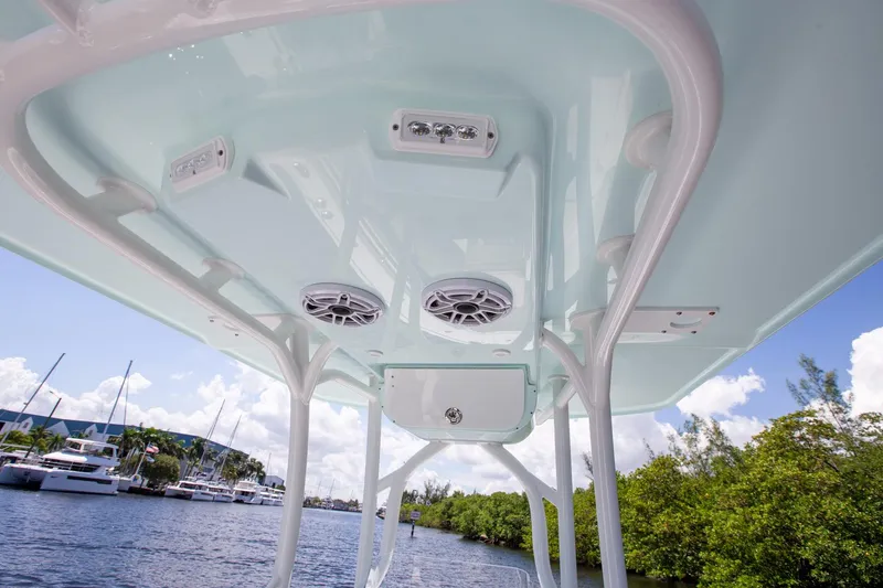 Slide: The Image of 2022 Yellowfin 26 Hybrid boat canopy with speakers and lights, docked near lush greenery. - 13