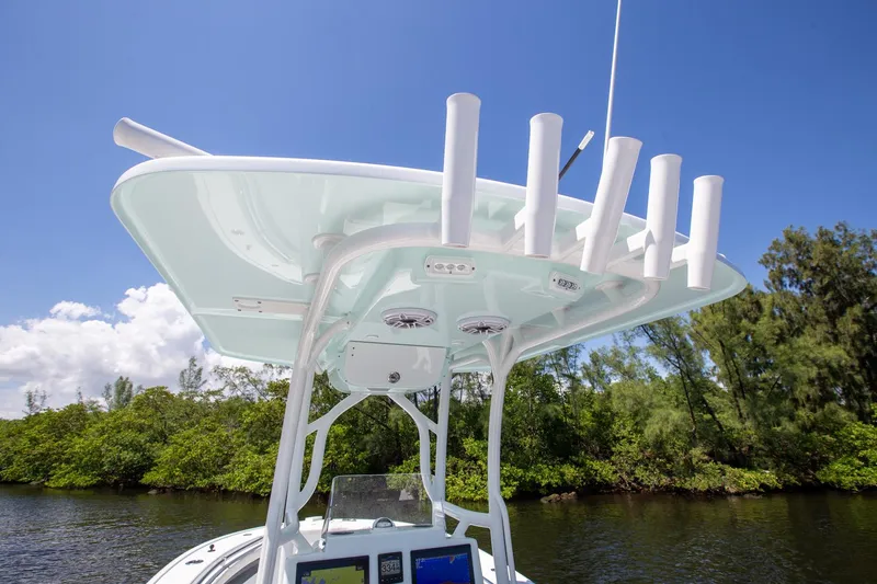 Slide: The Image of 2022 Yellowfin 26 Hybrid boat with rod holders, blue sky, and lush greenery. - 16