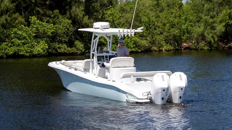 Slide: The Image of 2022 Yellowfin 26 Hybrid boat on calm water, surrounded by lush greenery. - 2
