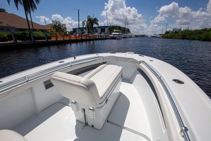 Slide: The Image of 2022 Yellowfin 26 Hybrid boat on a sunny waterway, featuring sleek white seating. - 5