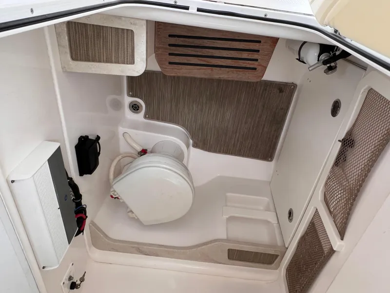 Slide: The Image of Interior of 2018 Everglades 273CC boat, featuring a compact marine toilet and storage compartments. - 11